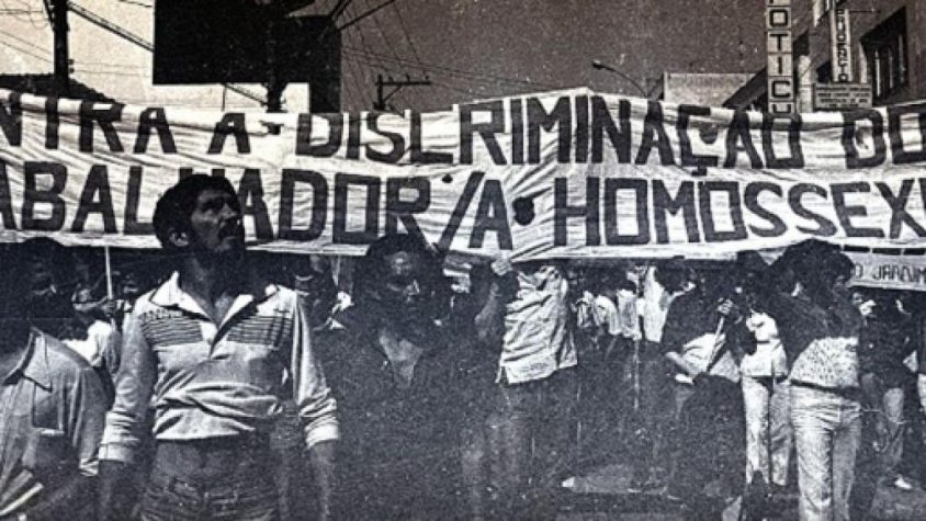 Foto antiga de grupo protestando contra a discriminação das comunidades LGBTI+.