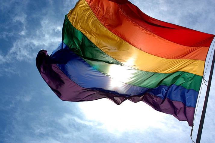 Bandeira arco-íris (LGBTQI+) tremulando sob um céu azul.